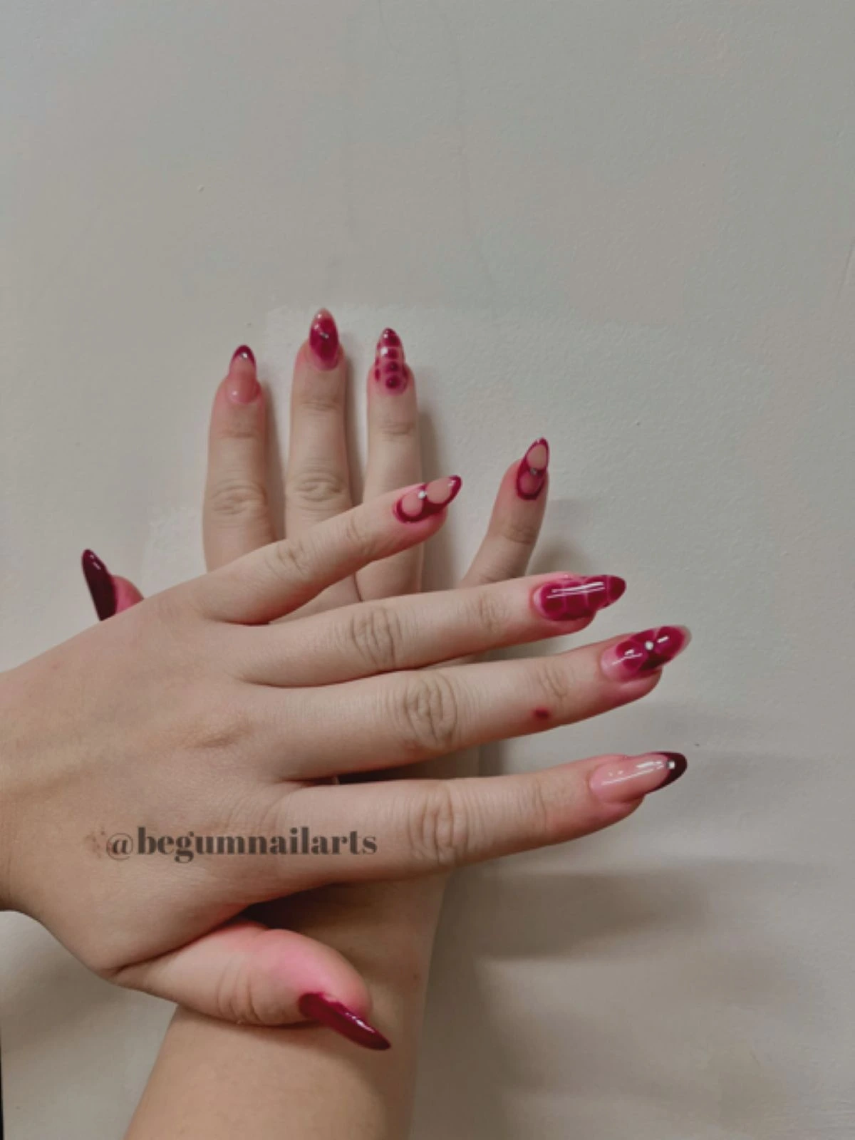 Baş tırnağına bordo, işaret tırnağına ten rengi üzerine bordo french ve kalan üç tırnağına kırmızı ve ten rengi karışık nail art yapılmış bir kadının elleri