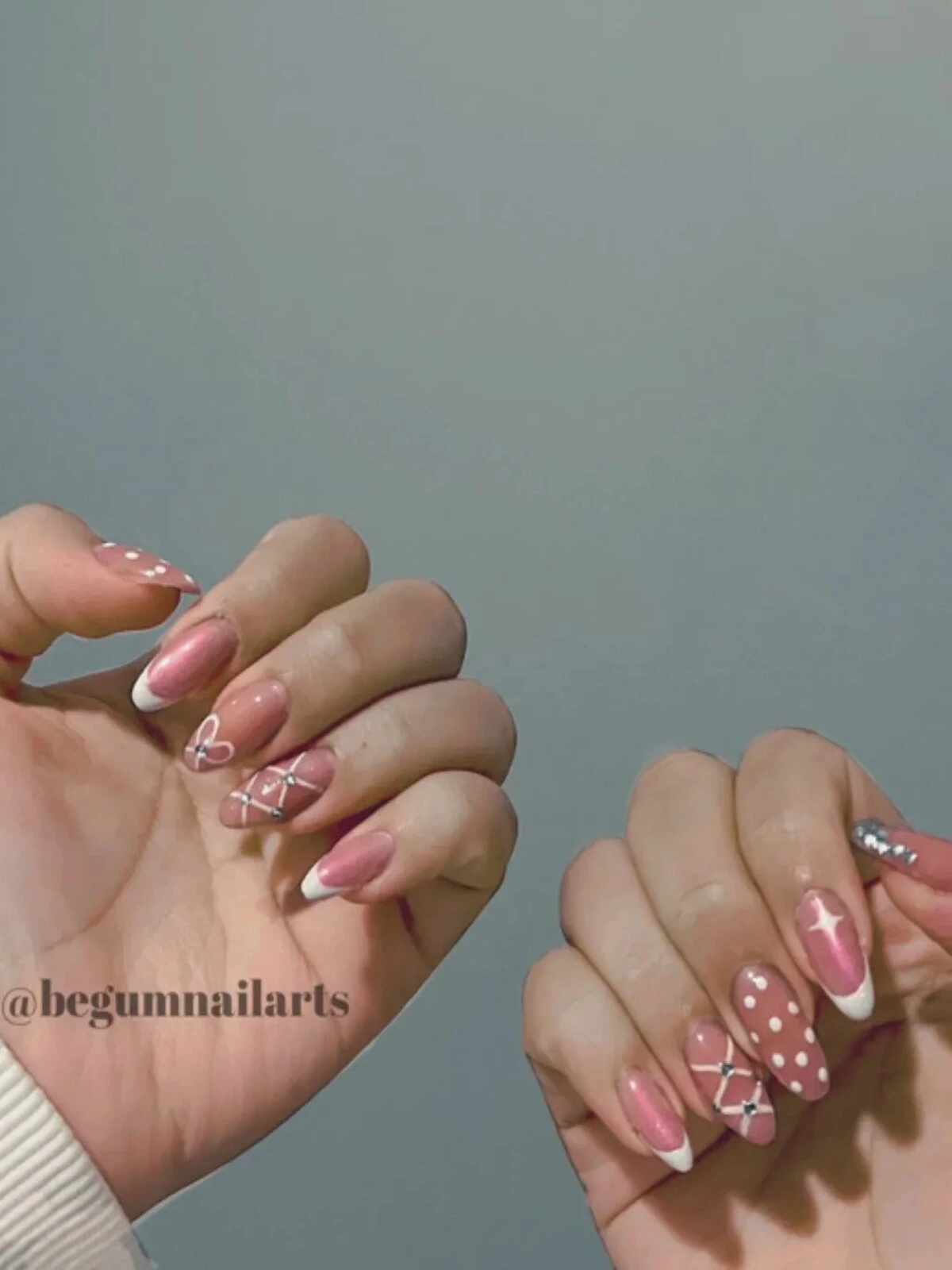 Tırnaklarına pembe rengi üzerine french, puantiye, ışıltılı taşlar gibi her tırnağa farklı nail art uygulaması yapılmış bir kadının elleri